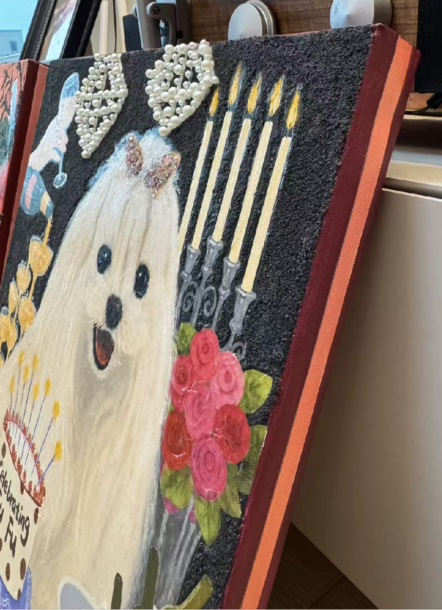 Angled view of a finished pet portrait with pearl-like decorative beads attached to the surface.